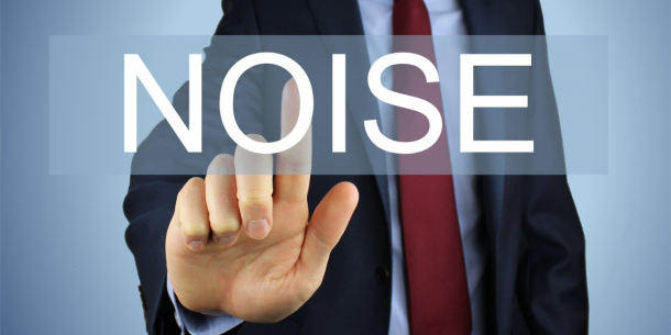 A man in a suit extends his finger to the screen to tap on the letter O in the word NOISE